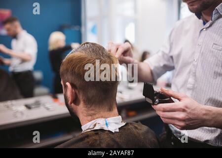 Gros plan sur la coupe tendance de l'homme au salon de coiffure. Homme hairstylist service client, faire coupe à l'aide de la machine et co Banque D'Images