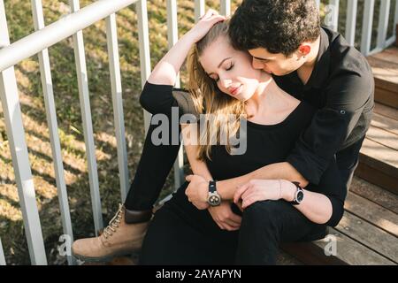 Beau jeune couple multiracial, couple étudiant en amour, asseyez-vous escalier en bois dans la ville. Magnifique guette de type brunette turque Banque D'Images