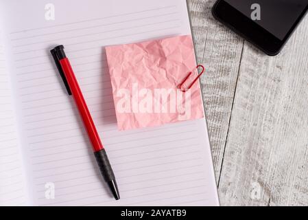 Papier à note froissé et un carnet placé au-dessus de la table en bois. Drap froissé plus bâton fixe à l'arrière-plan classique à tilte Banque D'Images