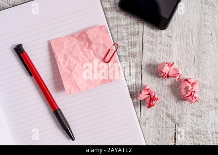 Papier à note froissé et un carnet placé au-dessus de la table en bois. Drap froissé plus bâton fixe à l'arrière-plan classique à tilte Banque D'Images