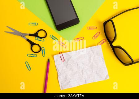 Vue avant feuilles de papier blanc de couleur clips crayon smartphone ciseaux lunettes couleur arrière-plan. Texte vide important futur Banque D'Images