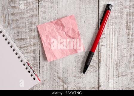 Papier à note froissé et un carnet placé au-dessus de la table en bois. Drap froissé plus bâton fixe à l'arrière-plan classique à tilte Banque D'Images