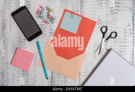 Enveloppe de couleur ouverte feuille vierge papier notes collantes clips de bille bloc-notes ciseaux smartphone reposant rétro vintage rustique vieux Banque D'Images