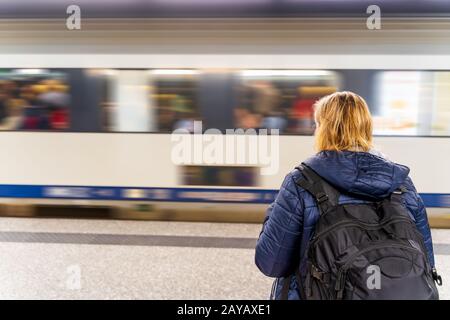 Femme attendant un train dans une station de métro non reconnaissable, flou de mouvement