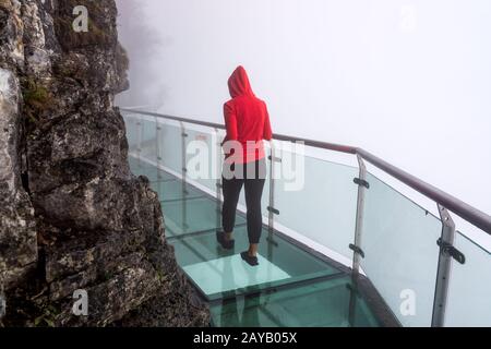 Femme marchant sur le verre à pied du ciel à la montagne Tianmen, brume, Zhangjiajie, Hunan, Chine Banque D'Images