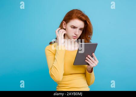 Gros plan Portrait jeune beau beau gingembre tendre redhair fille heureux souriant sur table numérique avec quelque chose de gueule. Bl Banque D'Images