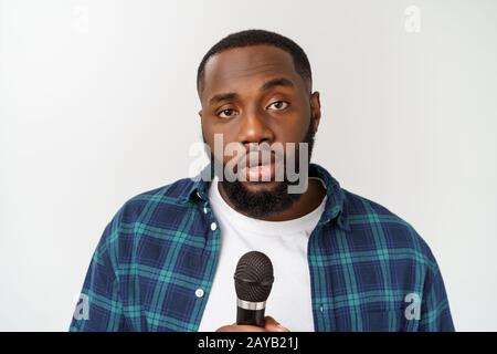 Handsome young african american boy chantant avec microphone émotionnelle isolé sur fond blanc. Banque D'Images