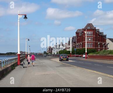 un couple plus âgé marchant en voiture marine à southport merseyside avec de vieux bâtiments d'hôtel bordant la rue un été lumineux Banque D'Images