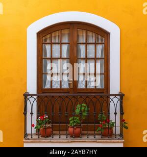 Balcon dans le centre-ville de sucre décoré de fleurs et d'une façade de style colonial jaune, Bolivie. Banque D'Images