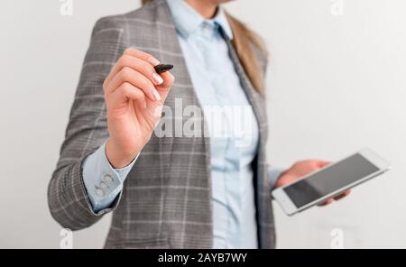 Femme d'affaires pointant dans un espace vide avec un stylo et un téléphone portable. Image de concept d'affaires avec une femme d'affaires porte un crayon. Banque D'Images