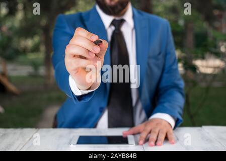 Homme d'affaires tient le stylo et pointe dans l'espace de copie. Homme avec le dessus de tour et le stylo dans la main. Concept d'affaires avec homme dans la suite W Banque D'Images