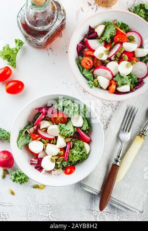 Salade avec tomates cerises, mozzarella et radsh, mélange de laitue Banque D'Images