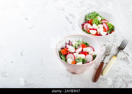 Salade avec tomates cerises, mozzarella et radsh, mélange de laitue Banque D'Images