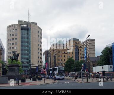 les bus et les piétons traversant la route sur la place de la ville de leeds avec de grands immeubles de bureaux de la rangée de parc Banque D'Images