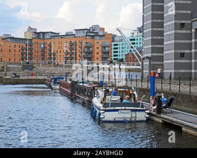 les gens sur les bateaux amarrés à leeds amarrer avec des immeubles d'appartements environnants Banque D'Images