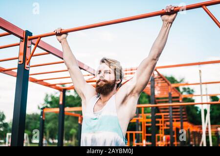 un athlète fort qui se tire sur la barre horizontale. Homme musclé qui fait des prises sur la barre horizontale dans le parc. Barre De Gymnastique Pendant Le Travail Banque D'Images