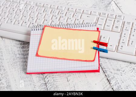 Bloc-notes en papier carré avec une note vide en forme de rectangle ci-dessus épinglée par deux clous de giropage sur la feuille. Clavier blanc sous a c Banque D'Images