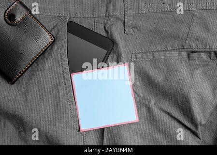 Smartphone dans la poche avant du pantalon avec portefeuille et papier bleu. Le gadget moderne est placé à l'intérieur du pantalon de l'homme près Banque D'Images