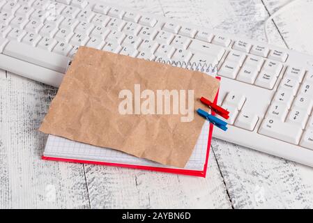 Bloc-notes en papier carré avec une note vide en forme de rectangle ci-dessus épinglée par deux clous de giropage sur la feuille. Clavier blanc sous a c Banque D'Images
