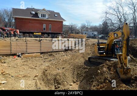 Une petite pelle hydraulique creuse un parking en sous-sol pour Les Maisons D'Attention nouveaux appartements pour les jeunes adultes sans abri, âgés de 18 à 24 ans. Banque D'Images