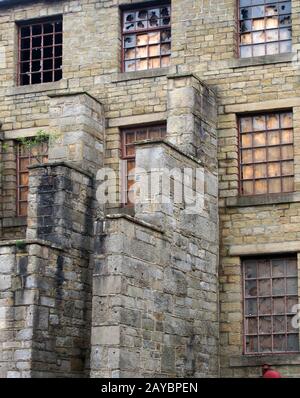 un grand bâtiment d'usine abandonné en décomposition avec des fenêtres en panne et en bord de bateau Banque D'Images