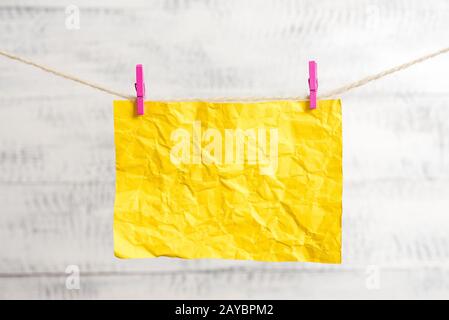 Note rectangulaire papier de couleur clippé dans une ligne de linge en clothespin dans un fond en bois blanc. Rappel vide carré A Banque D'Images