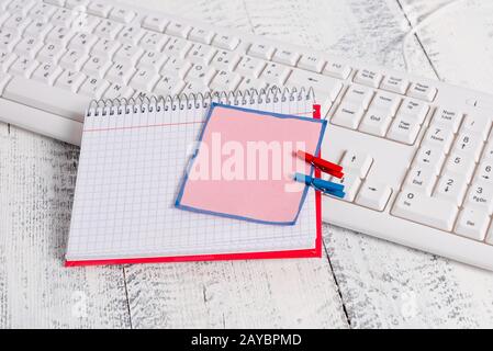 Bloc-notes en papier carré avec une note vide en forme de rectangle ci-dessus épinglée par deux clous de giropage sur la feuille. Clavier blanc sous a c Banque D'Images