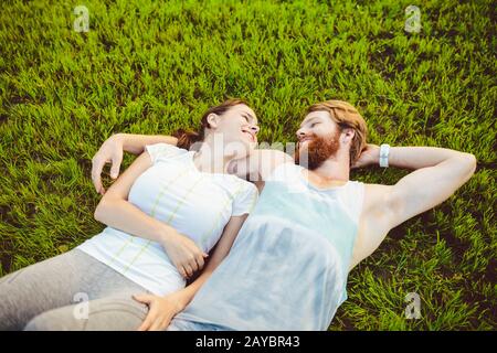 Le thème est le sport et un style de vie sain. Un jeune homme et un couple de femmes reposent sur leur dos sur l'herbe verte, une pelouse Banque D'Images