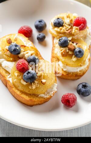 Toasts avec de la poire, le fromage à la crème, les noix et le miel. Banque D'Images