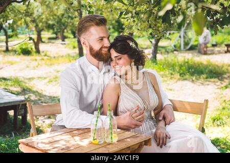 Couple séduisant jeunes mariés, moment heureux et joyeux. La mariée et le marié s'assoient à la table pour deux dans les bois. Concept romantique date. Banque D'Images
