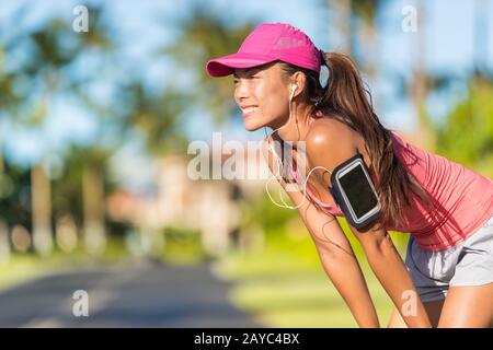 Bonne saison, une femme coureur de course à pied écoute de la musique sur le brassard de sport du téléphone avec écran tactile et écouteurs dans la rue de la ville, mode de vie actif. Fitness fille asiatique prête pour le jogging. Banque D'Images