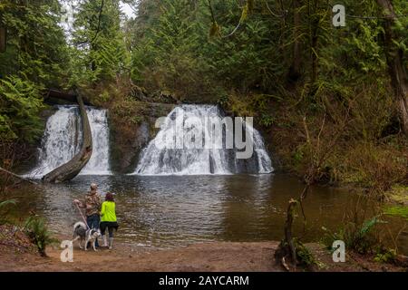 Un couple avec un chien aux chutes Cherry Creek dans les contreforts Central Cascade près de Duvall, Washington, États-Unis. Banque D'Images