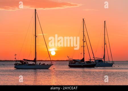 Trois voiliers en mer au coucher du soleil Banque D'Images