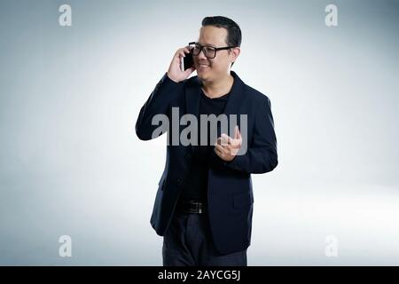 Un homme d'affaires souriant et heureux portant un costume noir et utilisant un smartphone moderne avec des points de pose de doigt. Banque D'Images