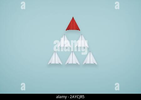 Un avion unique en papier rouge dirige le groupe d'avions en papier blanc sur fond bleu clair . Idée créative d'affaires ou de conception Banque D'Images