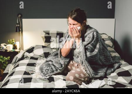 femme malade avec nez liquide, assise au lit. femme se sentant mal et éternuer chambre. Femme tenant des tissus, symptômes de la grippe. Santé Banque D'Images