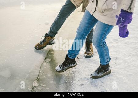 Essayer le danger du pied, tester la glace mince près de la rive. Deux amoureux marchent avec une promenade le long d'un lac gelé à pré Banque D'Images