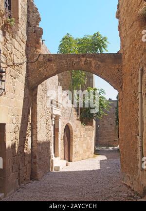 une rue pavée médiévale calme de la ville de rhodes avec de vieux bâtiments et des arches entre des bâtiments en pierre Banque D'Images