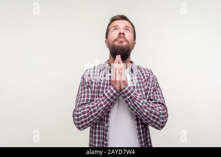 Portrait de l'homme barbu bouleversé dans une chemise de plaid à la recherche et à faire un geste de prière avec les mains, s'excusant de dire s'il vous plaît, désespéré expression. I Banque D'Images