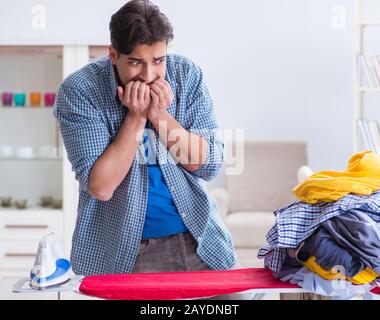 Jeune homme mari faire le repassage de vêtements à la maison Banque D'Images