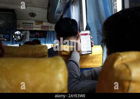 Mandaluyong City, Philippines - 13 février 2020: Le passager utilise son smartphone pour passer le temps en voyageant en bus. Banque D'Images