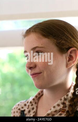 Une jolie jeune fille souriante, avec des yeux verts, des cheveux rouges, des freckles et des piquets. Banque D'Images