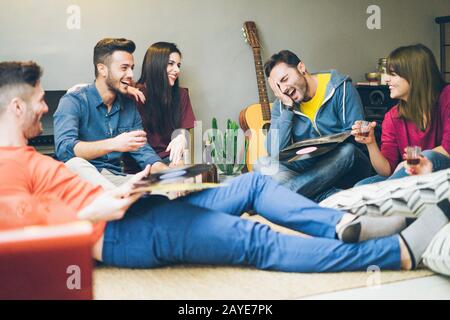 Heureux amis s'amuser dans le salon à la maison boire et rire - jeunes étudiants profitant du temps ensemble écouter de la musique avec des disques de vinyle - Main Banque D'Images