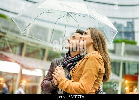 Jeune couple heureux sous une douce journée de pluie couvrant avec parapluie transparent dans le centre-ville de londres - Amoureux profitant de vacances ensemble - concept d'amour Banque D'Images
