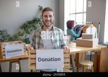 Jeune homme debout avec un tiroir de vêtements. Banque D'Images