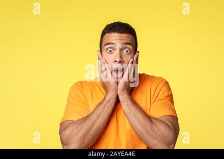 Un jeune homme surpris et sans voix a choqué le bel homme dans un t-shirt, stupéfié, la mâchoire de chute et l'appareil photo à craquer les yeux, saisir le visage Banque D'Images