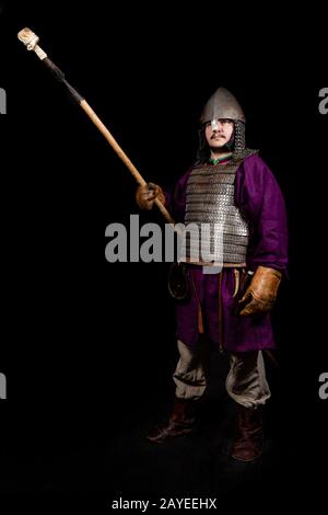 homme en robe médiévale, chemise violette, casque et chaîne de courrier contient une lance Banque D'Images