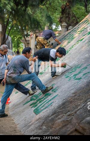 Homme peindre des personnages chinois de calligraphie sur un rocher Banque D'Images