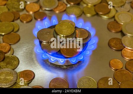 Pièces de monnaie sur le brûleur à gaz de la cuisinière de cuisine Banque D'Images