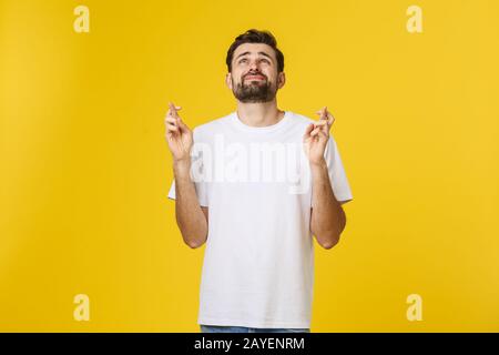 Jeune homme faisant un souhait isolé sur fond jaune Banque D'Images